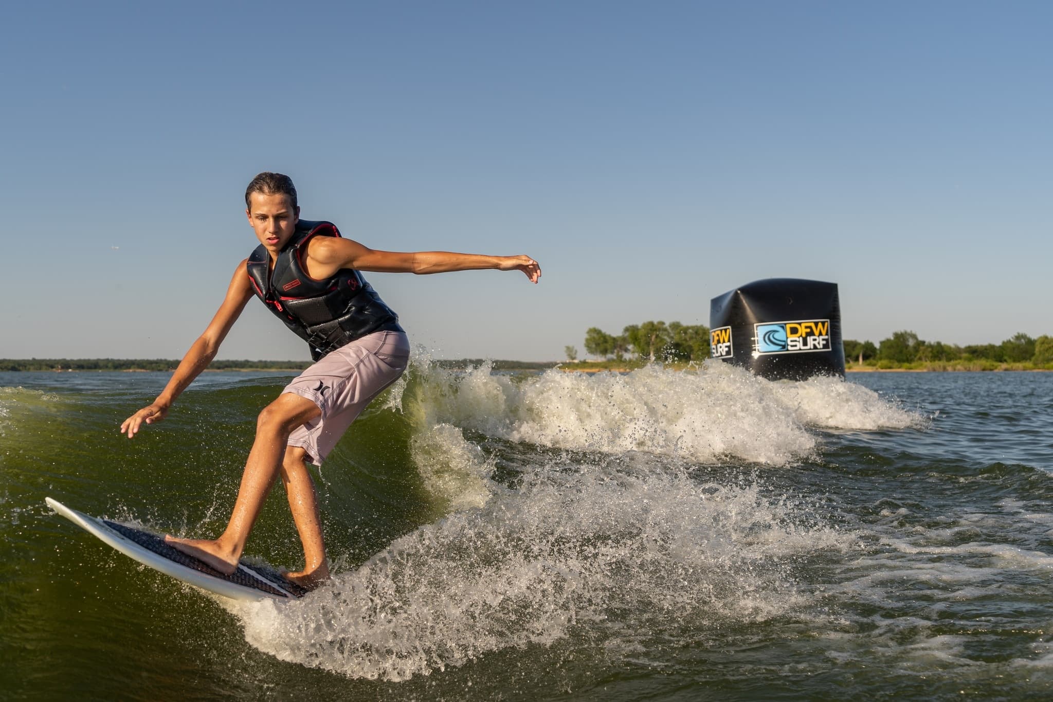 Towboat wake surfer riding waves on open water at Grapevine Lake
