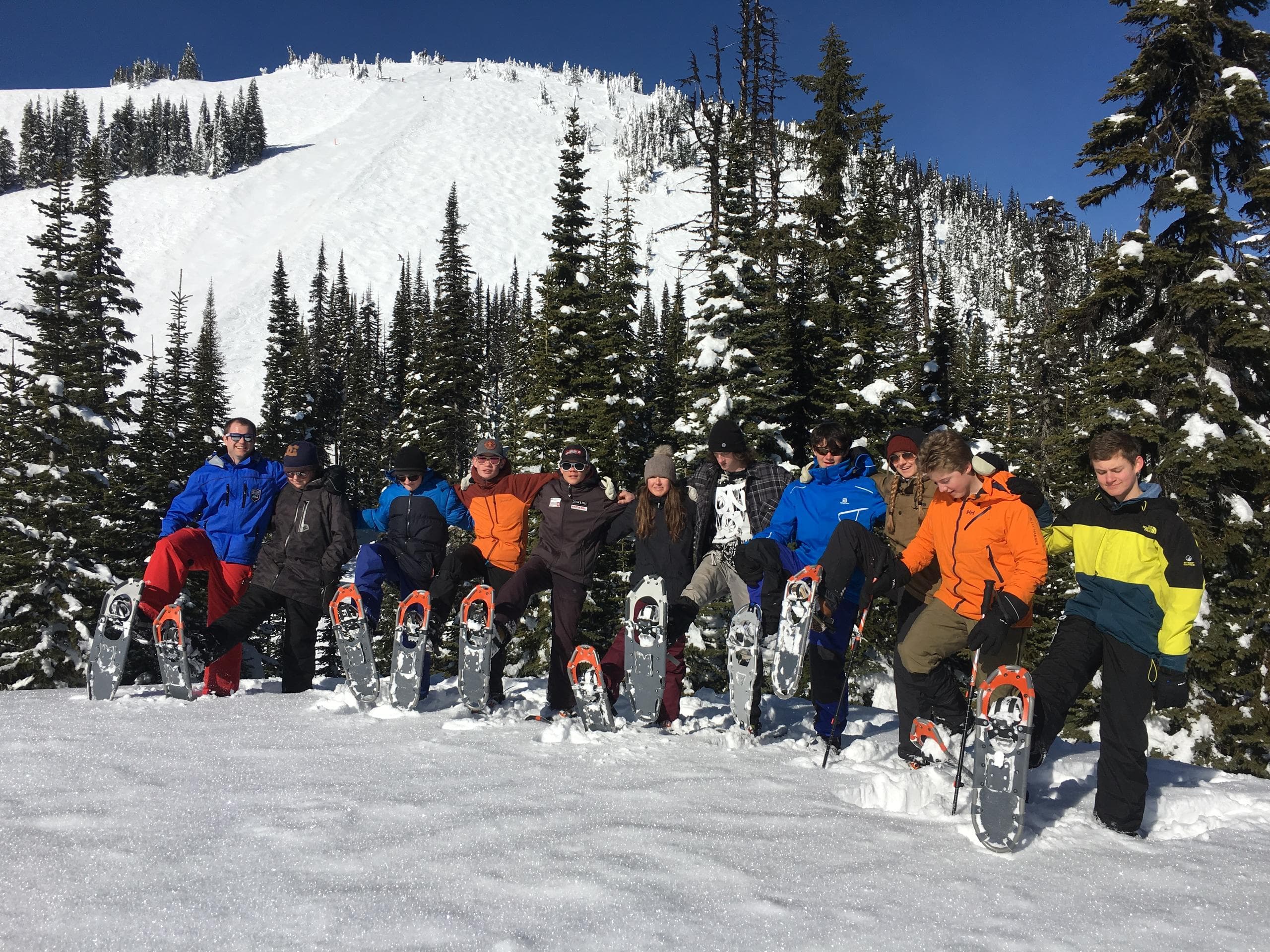Guided snowshoe group on snowy alpine slope beneath blue sky
