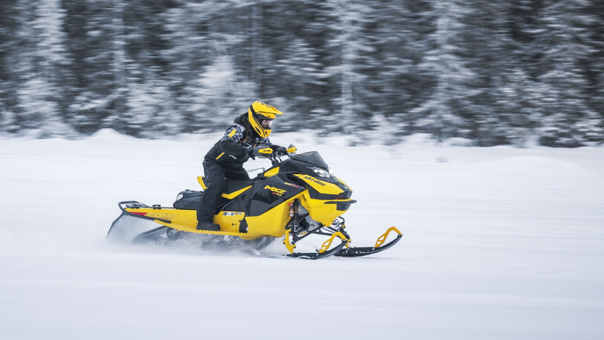 Snowmobile carving through powder on open snowy trail