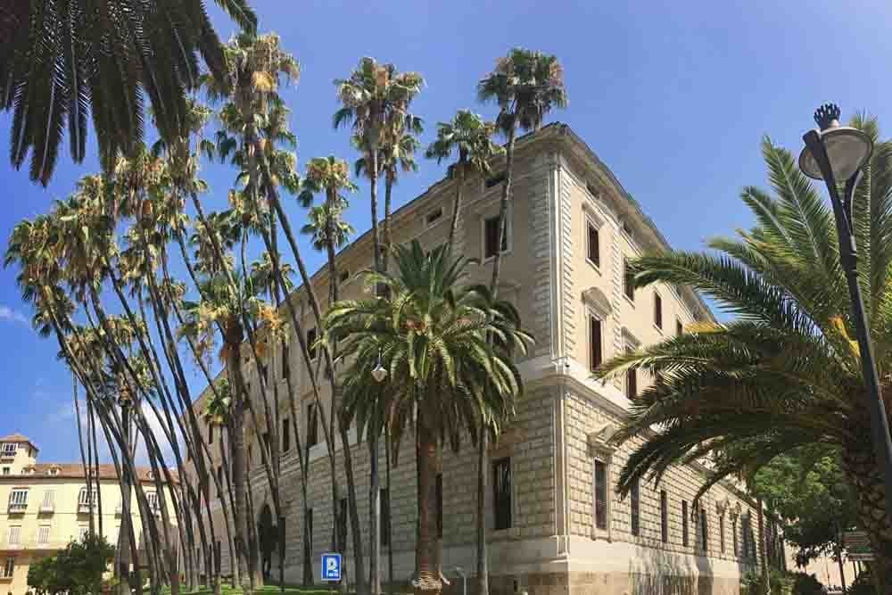 Historic seaside building framed by tall palms in Malaga