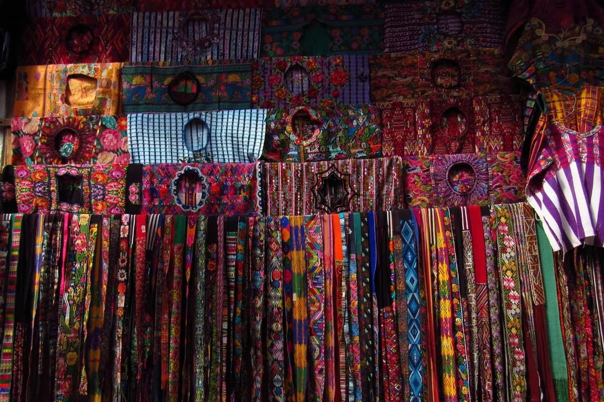 Colorful woven textiles and belts displayed in indoor market stall