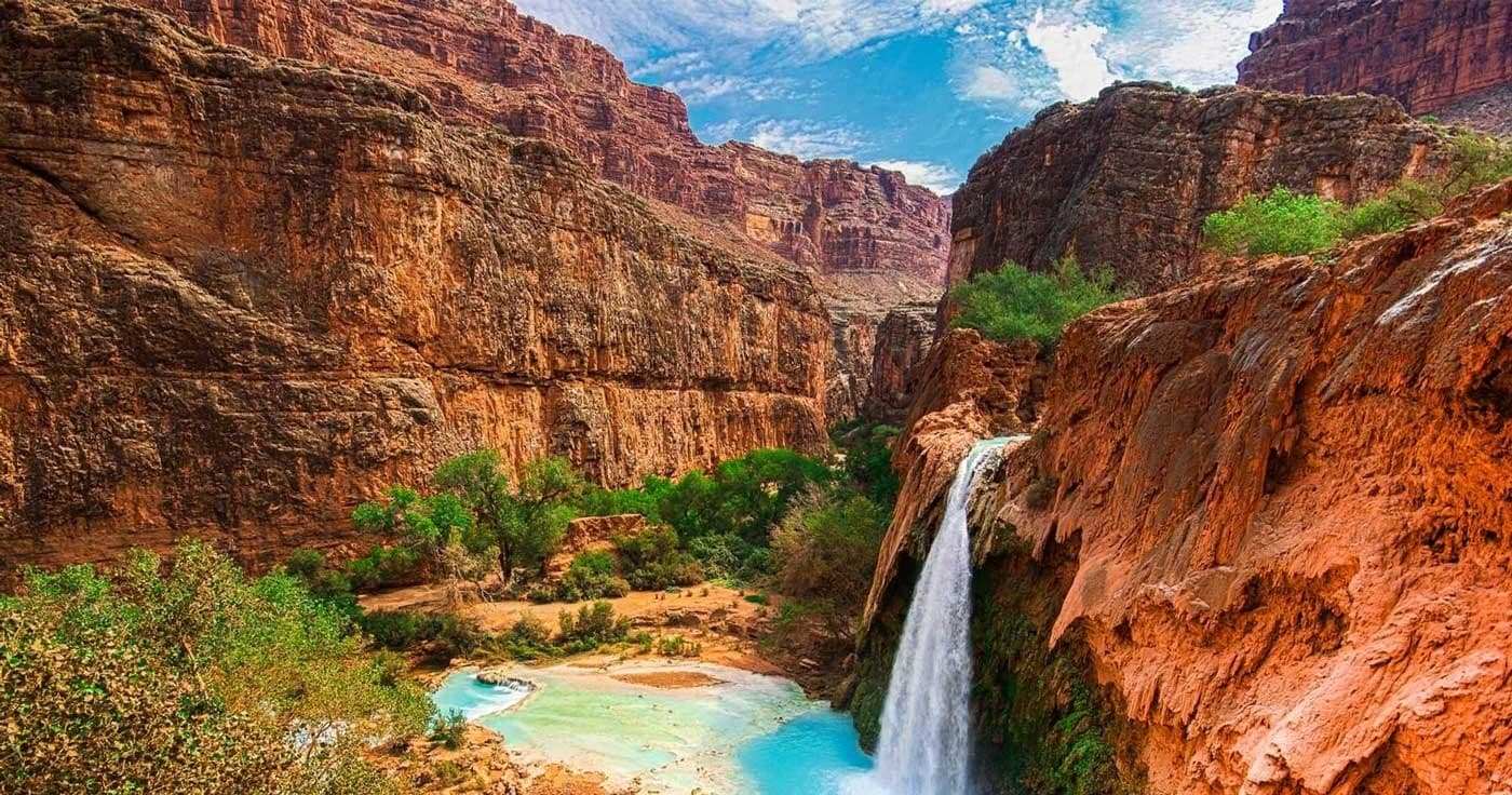 Waterfall cascading into turquoise pool in red canyon oasis