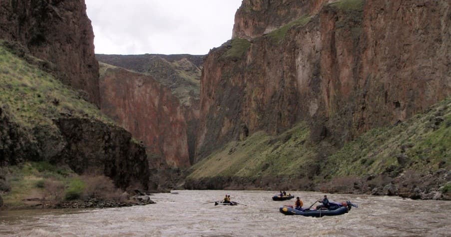 Rafts drifting through dramatic canyon river with panoramic cliffs