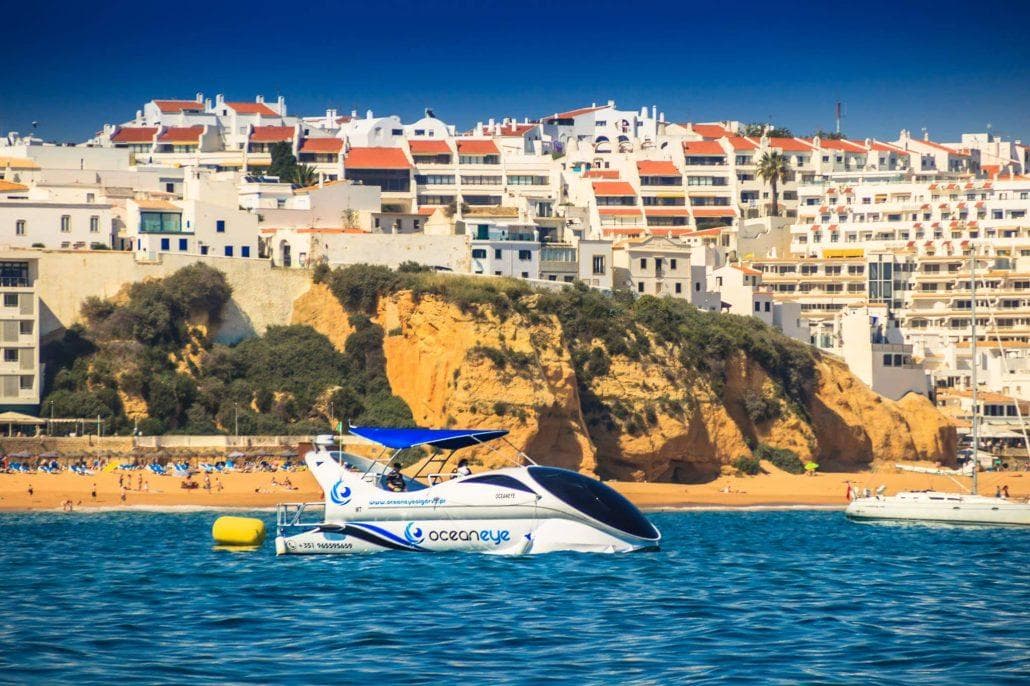 Coastal sightseeing boat off Algarve cliffs, sunny ocean cruise