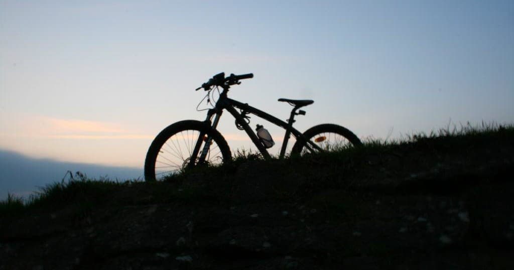 Mountain bike silhouette at dusk on ridgeline overlooking valley
