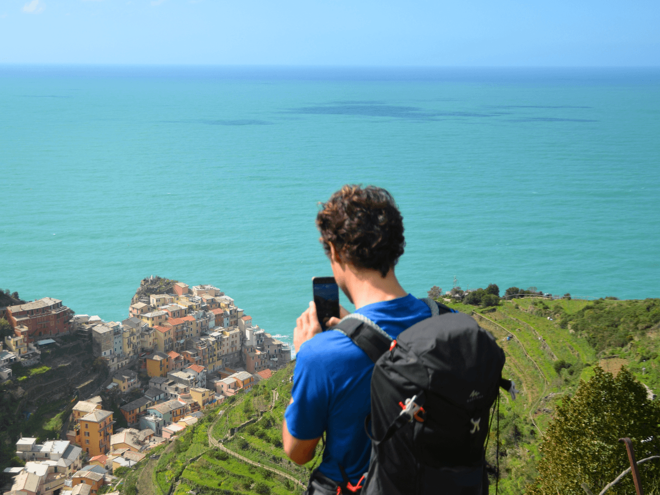 Hiker overlooking seaside village and turquoise Mediterranean