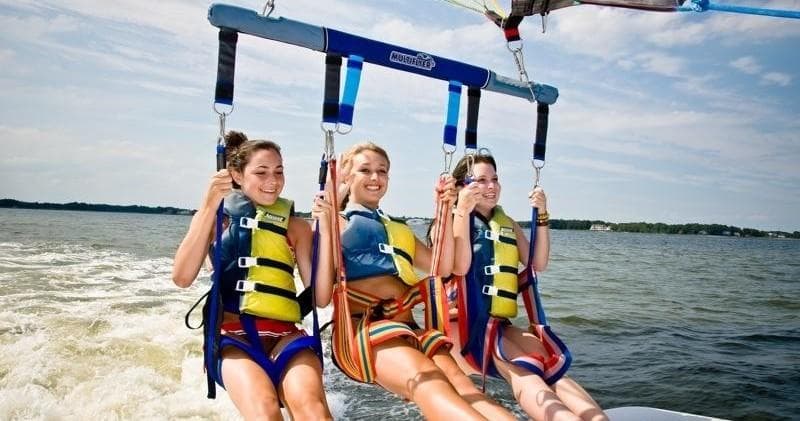 Three people parasailing over calm bay with horizon view