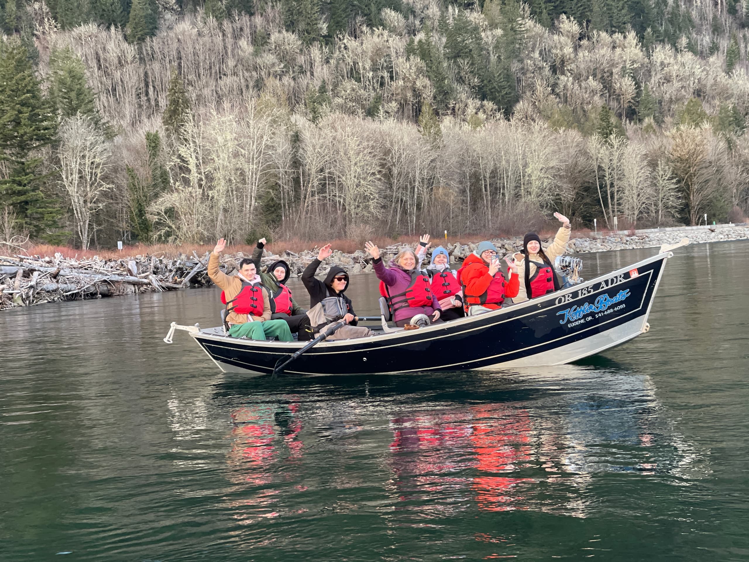 Passengers on a tour boat cruising calm coastal waters by forest