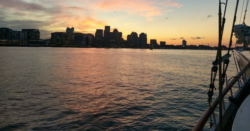Sunset sail with Boston skyline over calm harbor waters