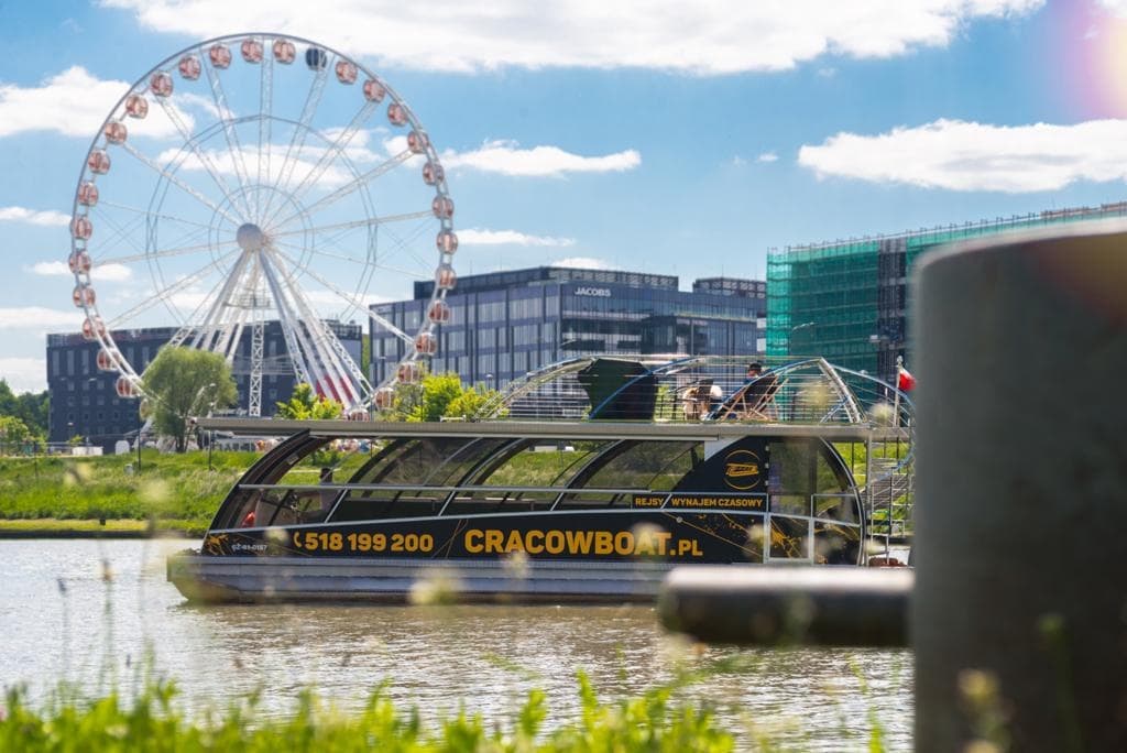 Ferris wheel and riverfront sightseeing boat in Krakow