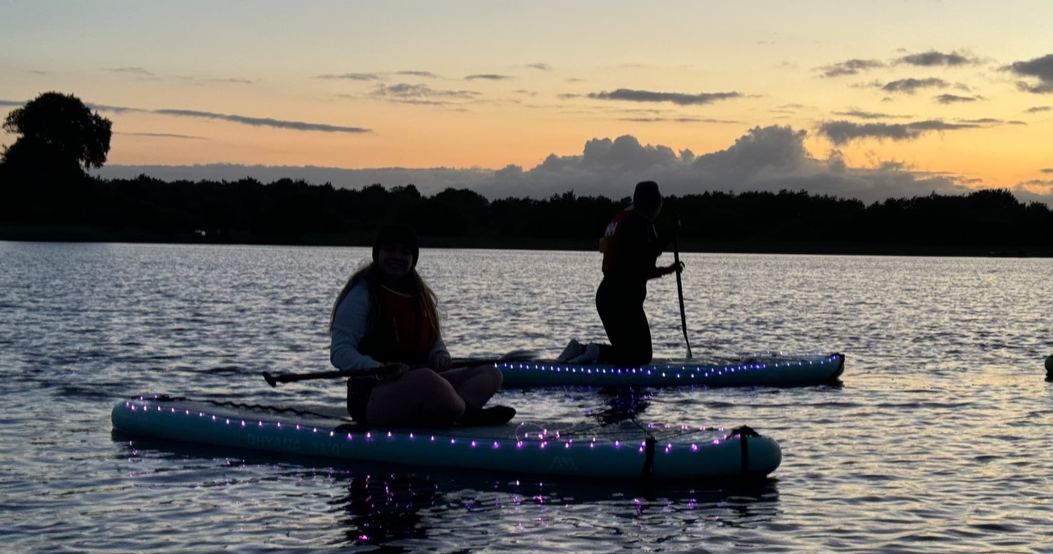 Solo paddler at dusk on lake with twilight horizon
