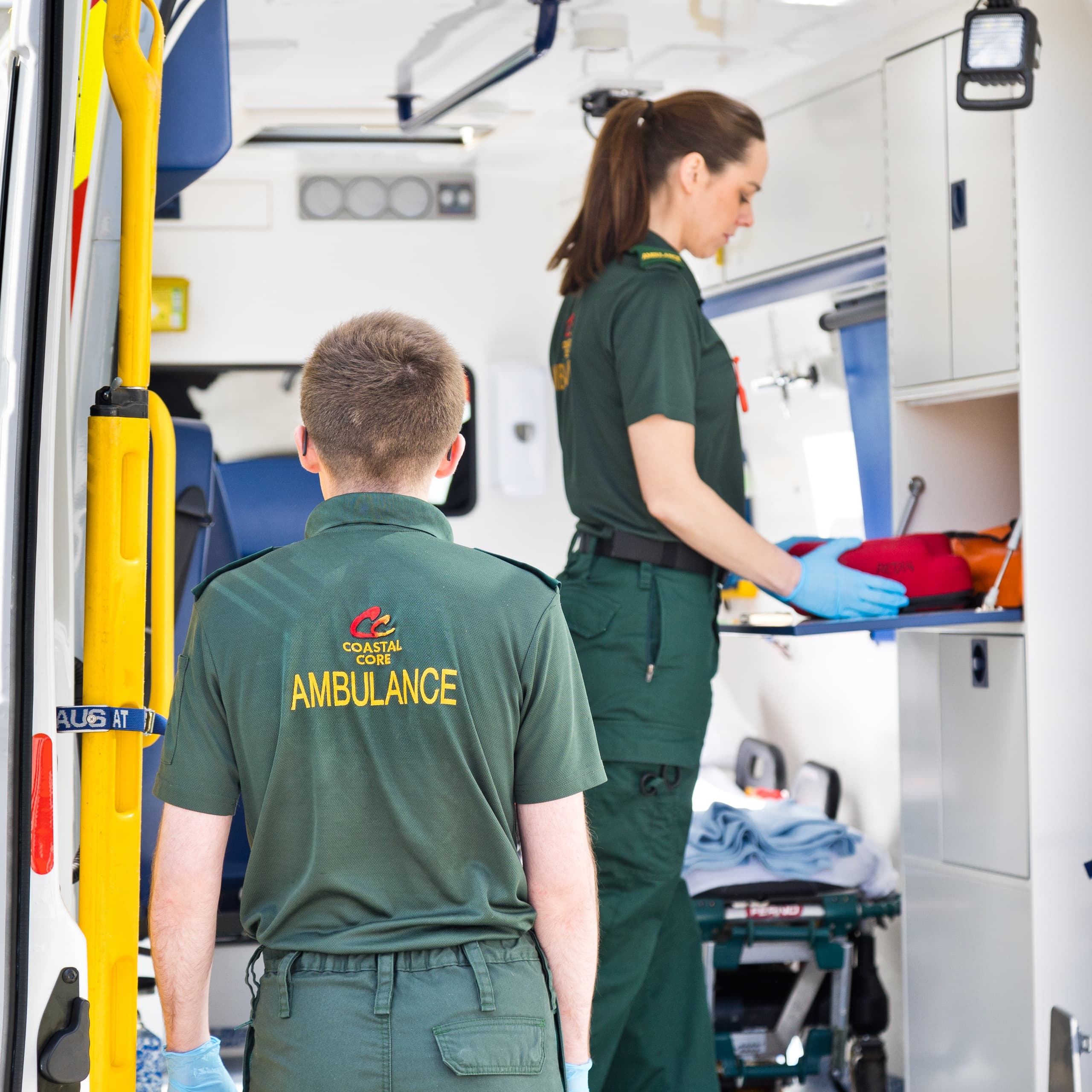 Ambulance crew organizing equipment inside emergency vehicle