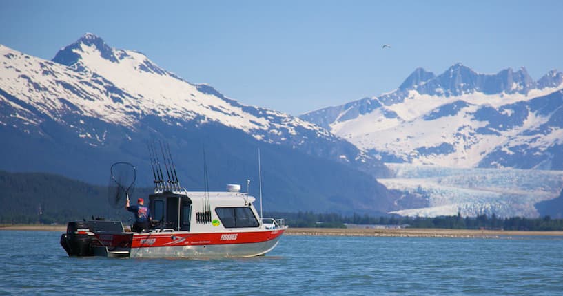 Fishing boat cruising an Alaskan inlet with snowcapped peaks