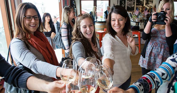 Friends toasting white wine at indoor tasting event and social