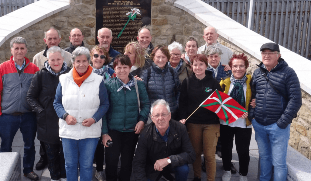 Tour group on steps holding Basque flag near historic memorial site