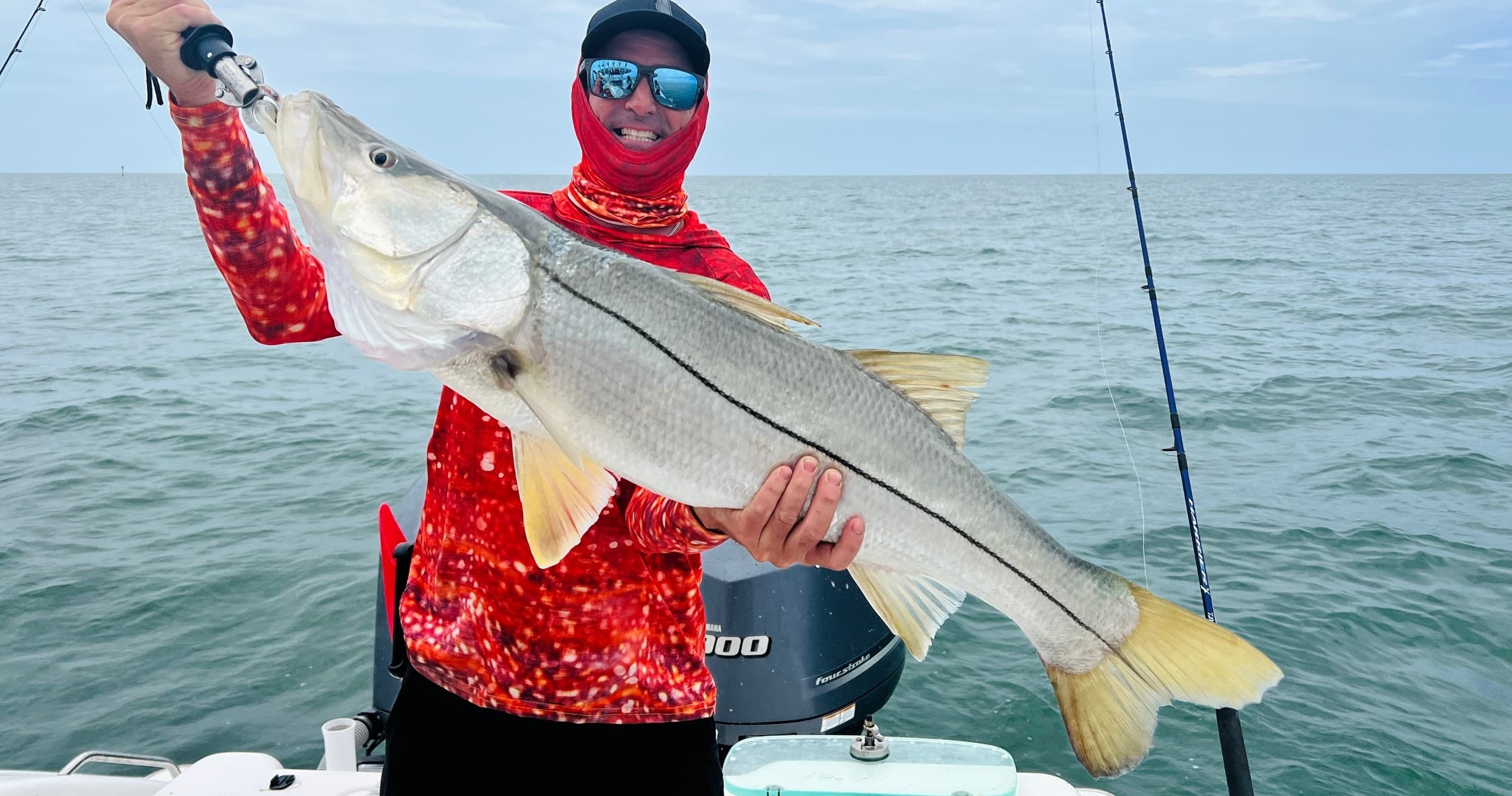 Angler holding large snook on offshore boat with ocean horizon