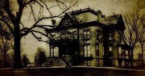 Victorian haunted mansion exterior on wooded lawn at dusk