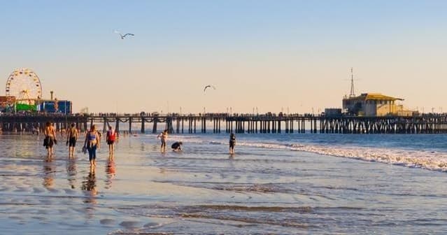 Beachgoers at pier on Pacific coast during golden hour