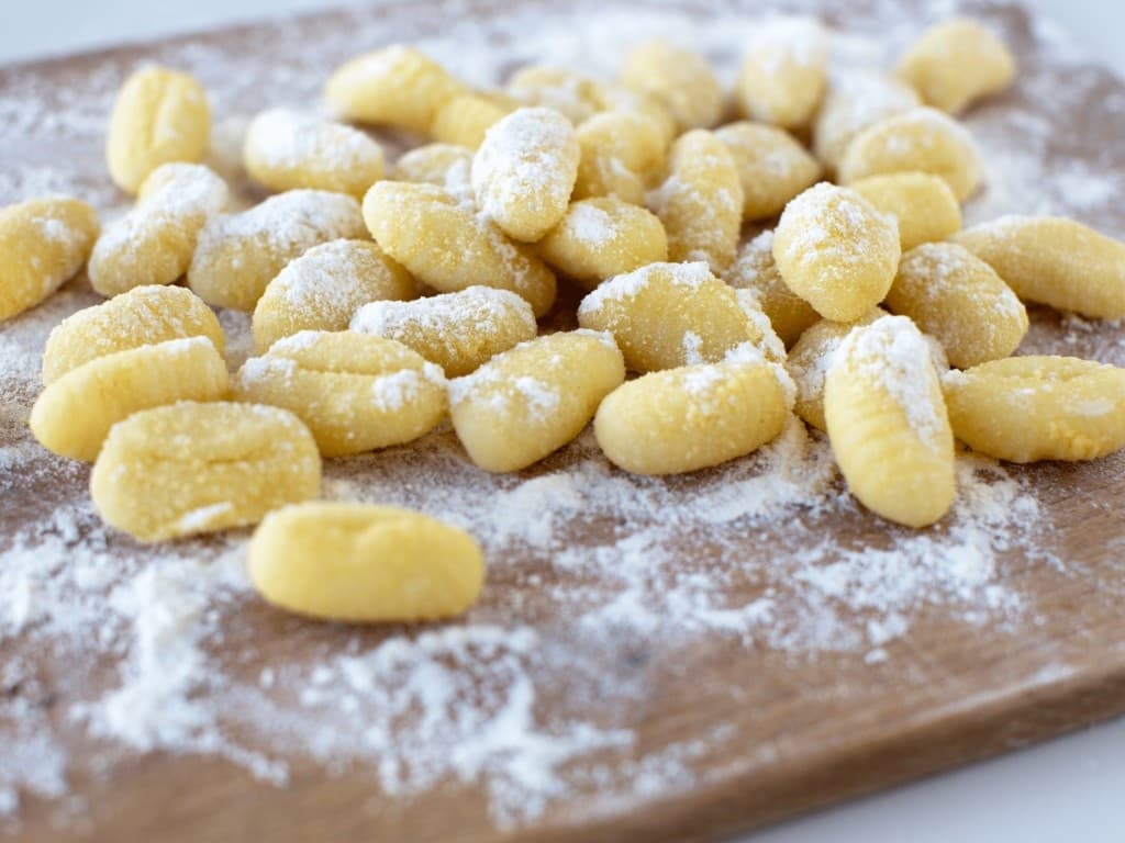 Homemade potato gnocchi dusted with flour on wooden board