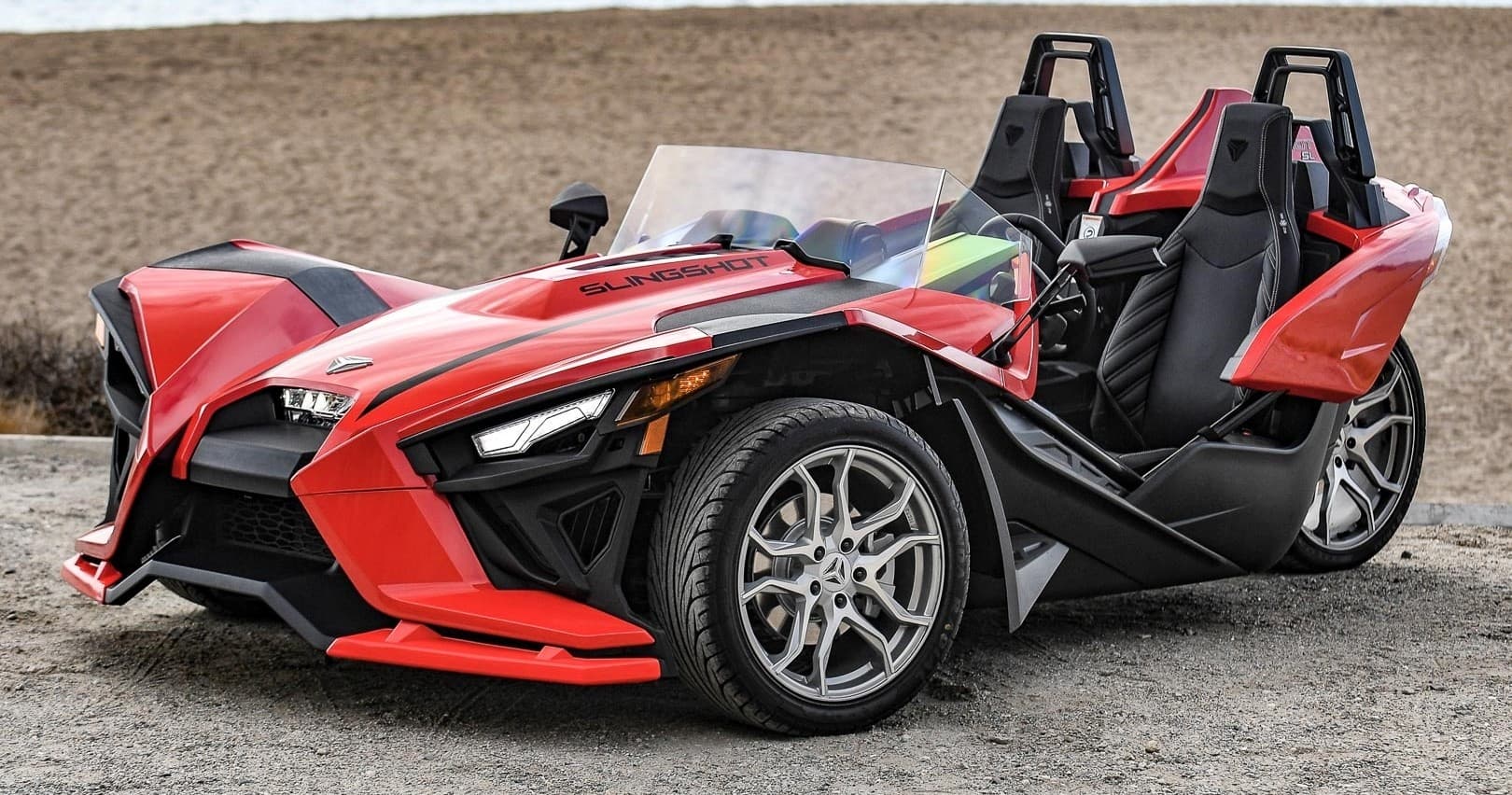 Red Polaris Slingshot parked on coastal road for scenic tour