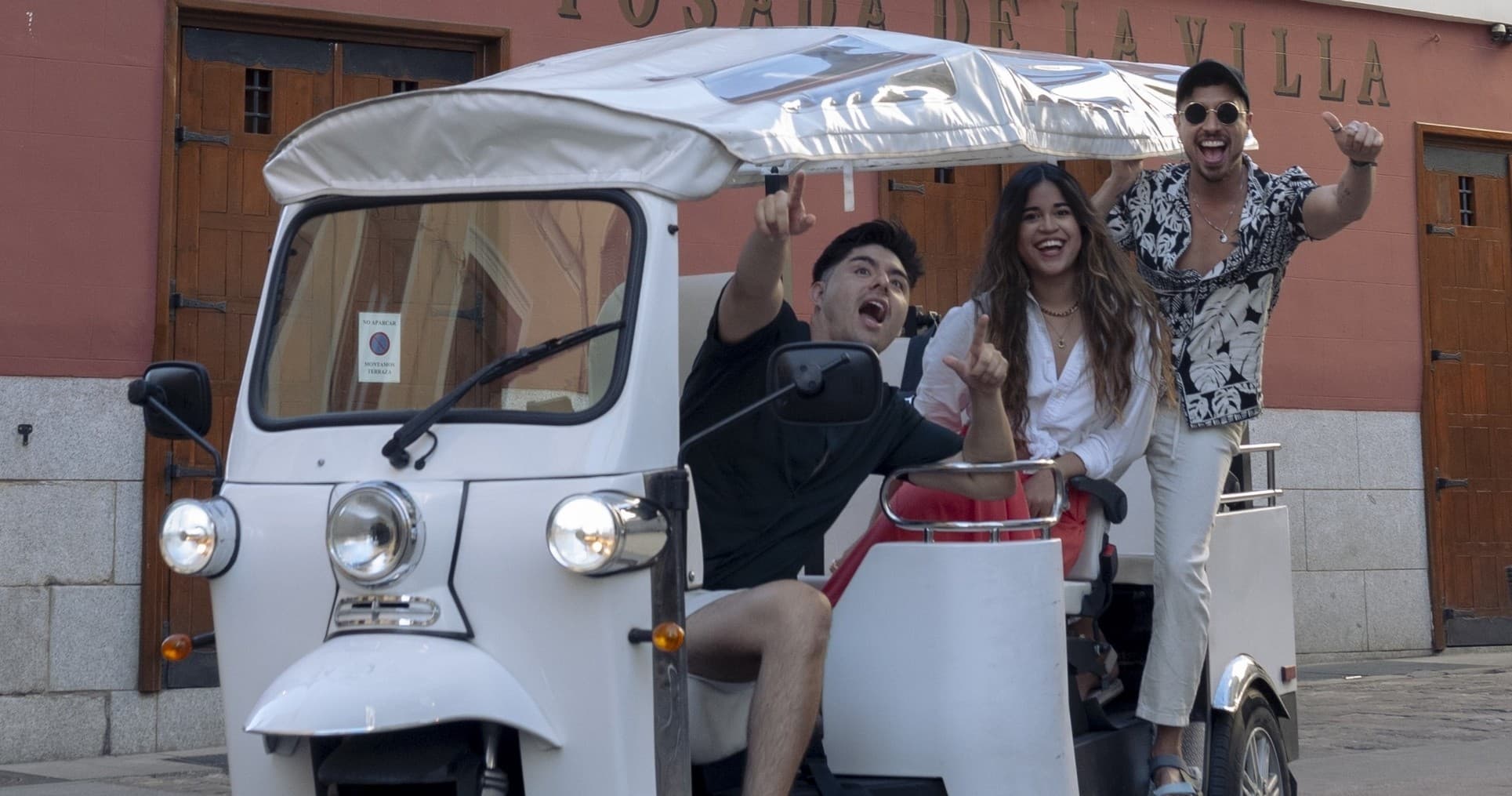 Frontal electric tuk-tuk tour in Madrid waving passengers onboard