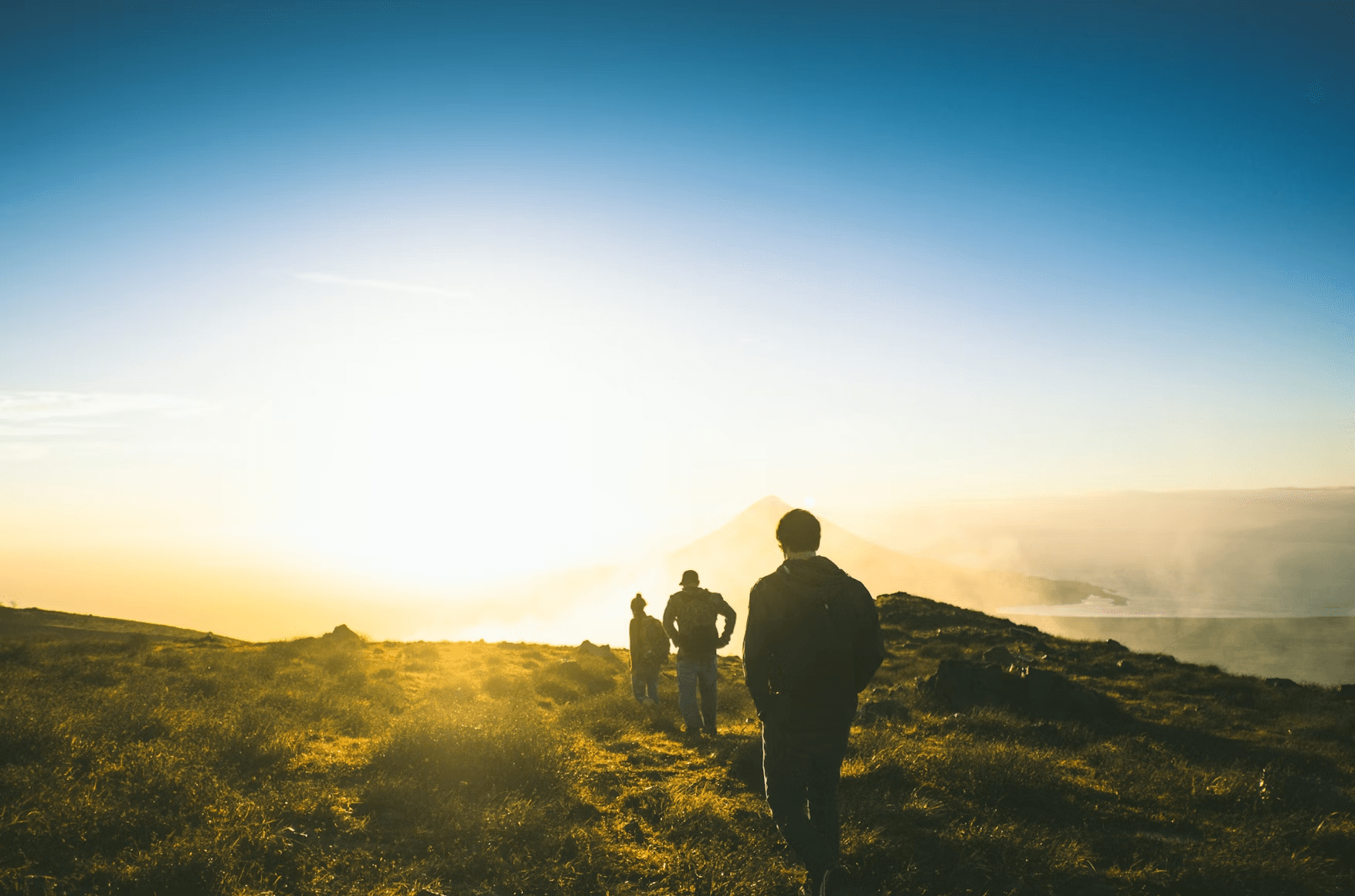 Hikers trekking toward sunrise on coastal ridge trail