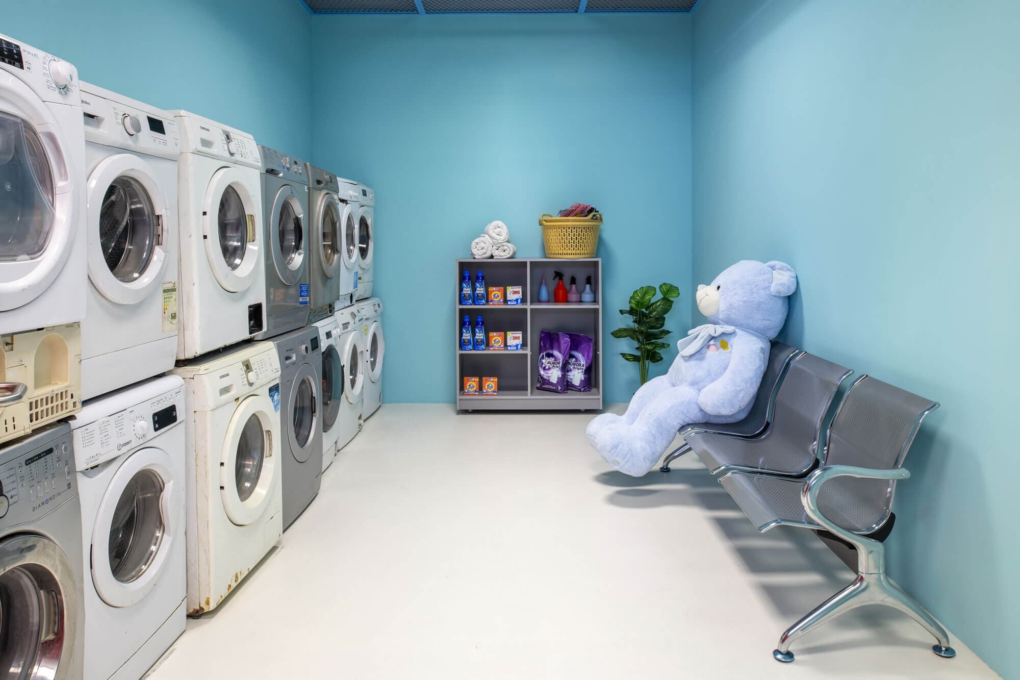 Bright laundromat interior with stacked machines and bench
