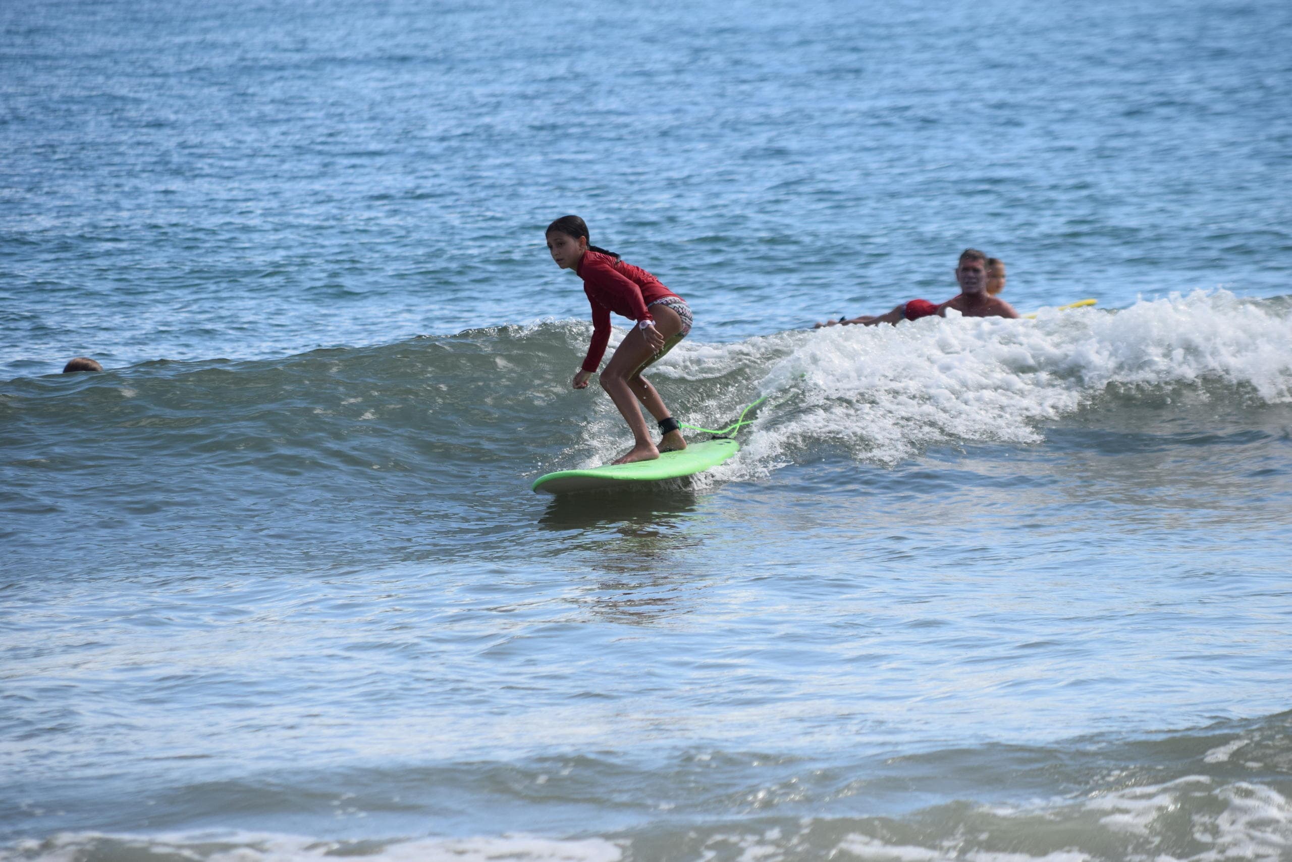 Surfer riding small breaking wave along open ocean shore