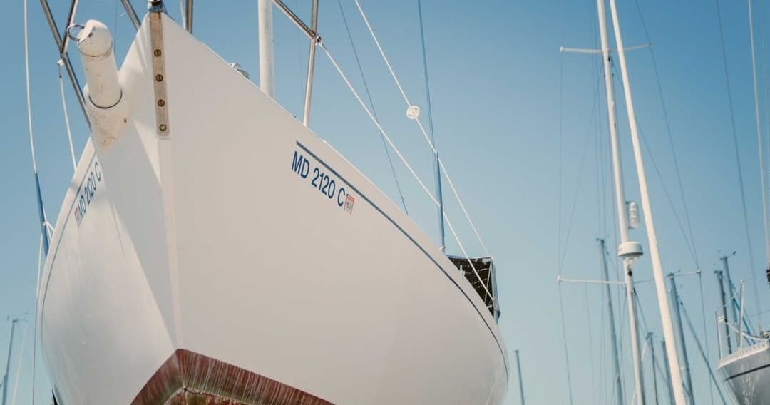 White sailboat hull in marina, moored on calm clear day