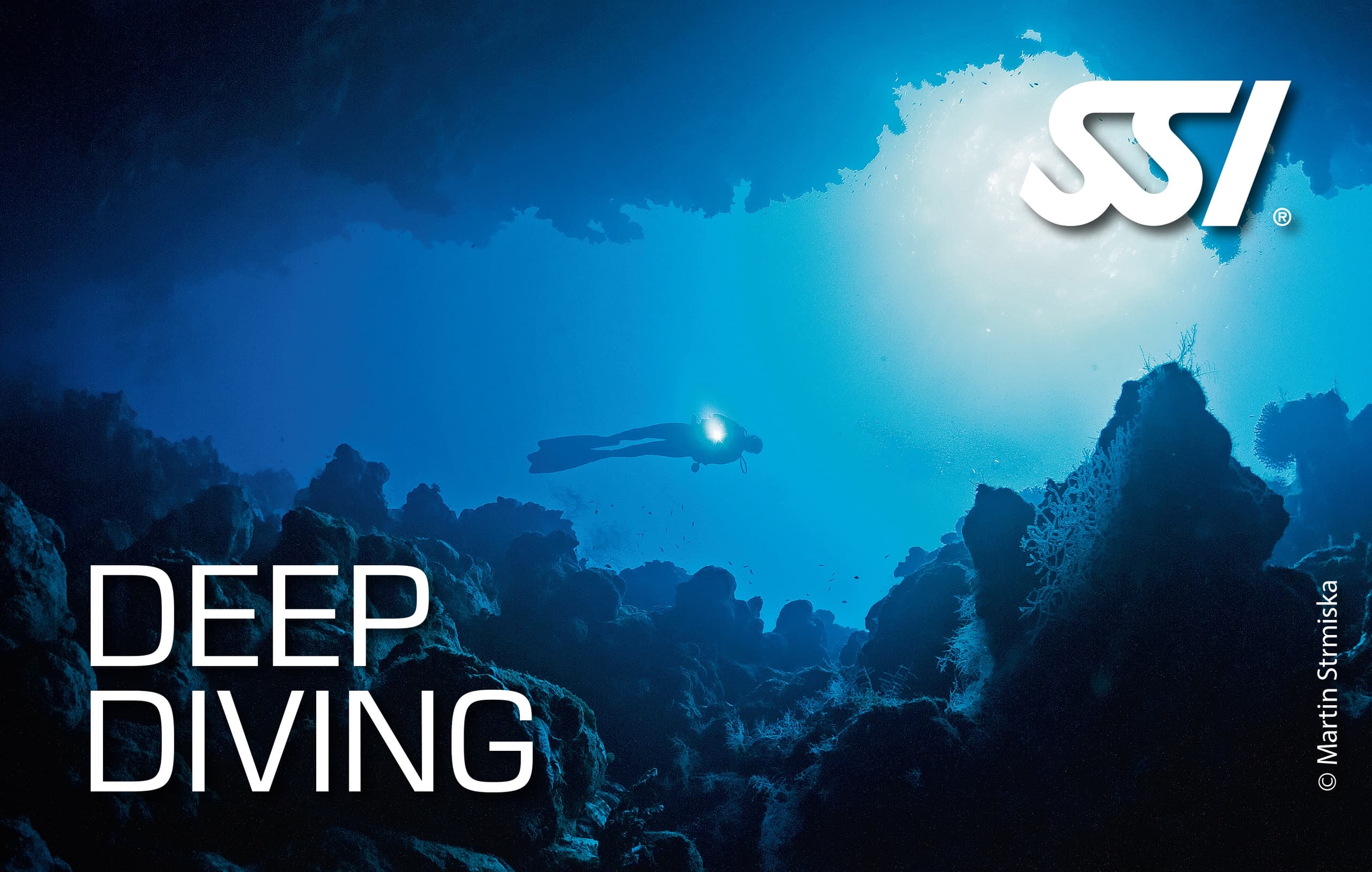 Deep scuba diving over dramatic blue seascape and reef coral