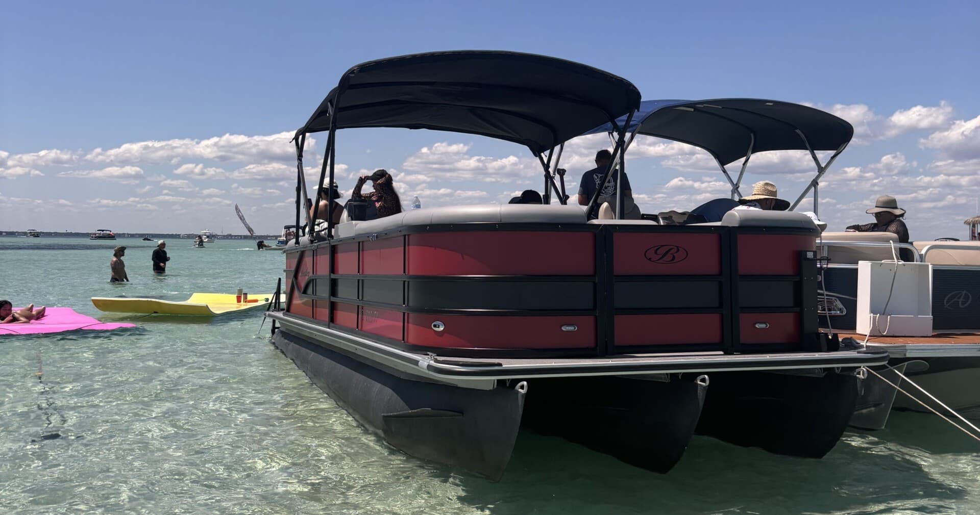 Pontoon boat anchored in clear shallow coastal waters at sandbar