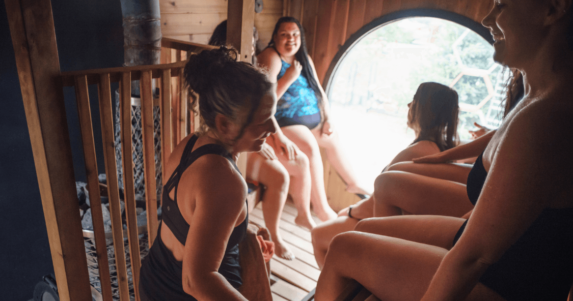 Group of people socializing inside cedar sauna room session