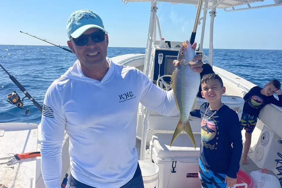 Angler holding fresh yellowtail on charter boat offshore