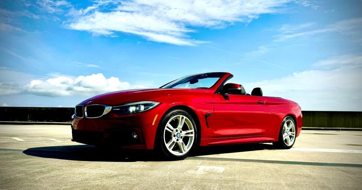 Red convertible sports car cruising coastal highway at sunset