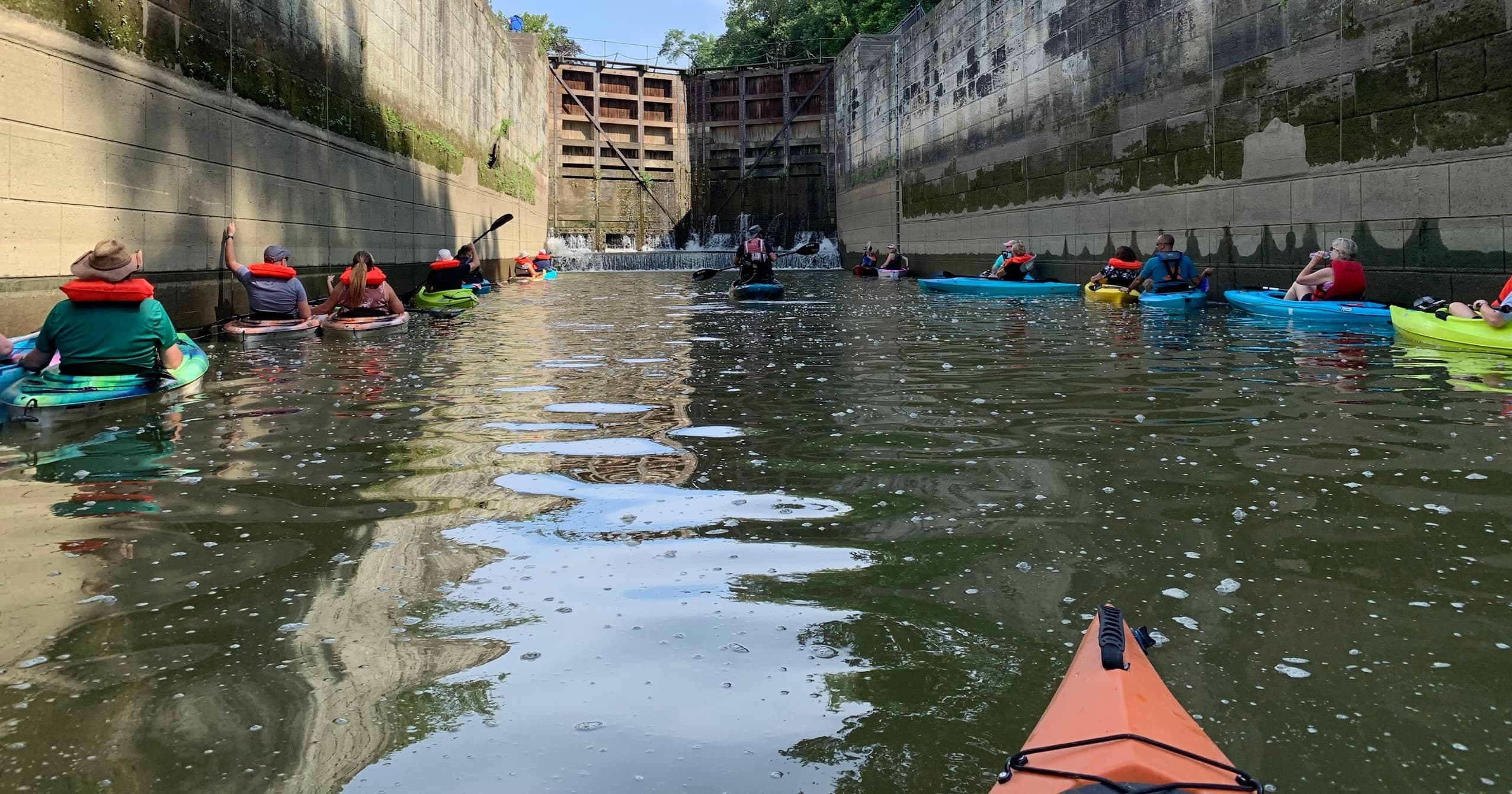 Kayak flotilla navigating narrow concrete lock channel in Zanesville