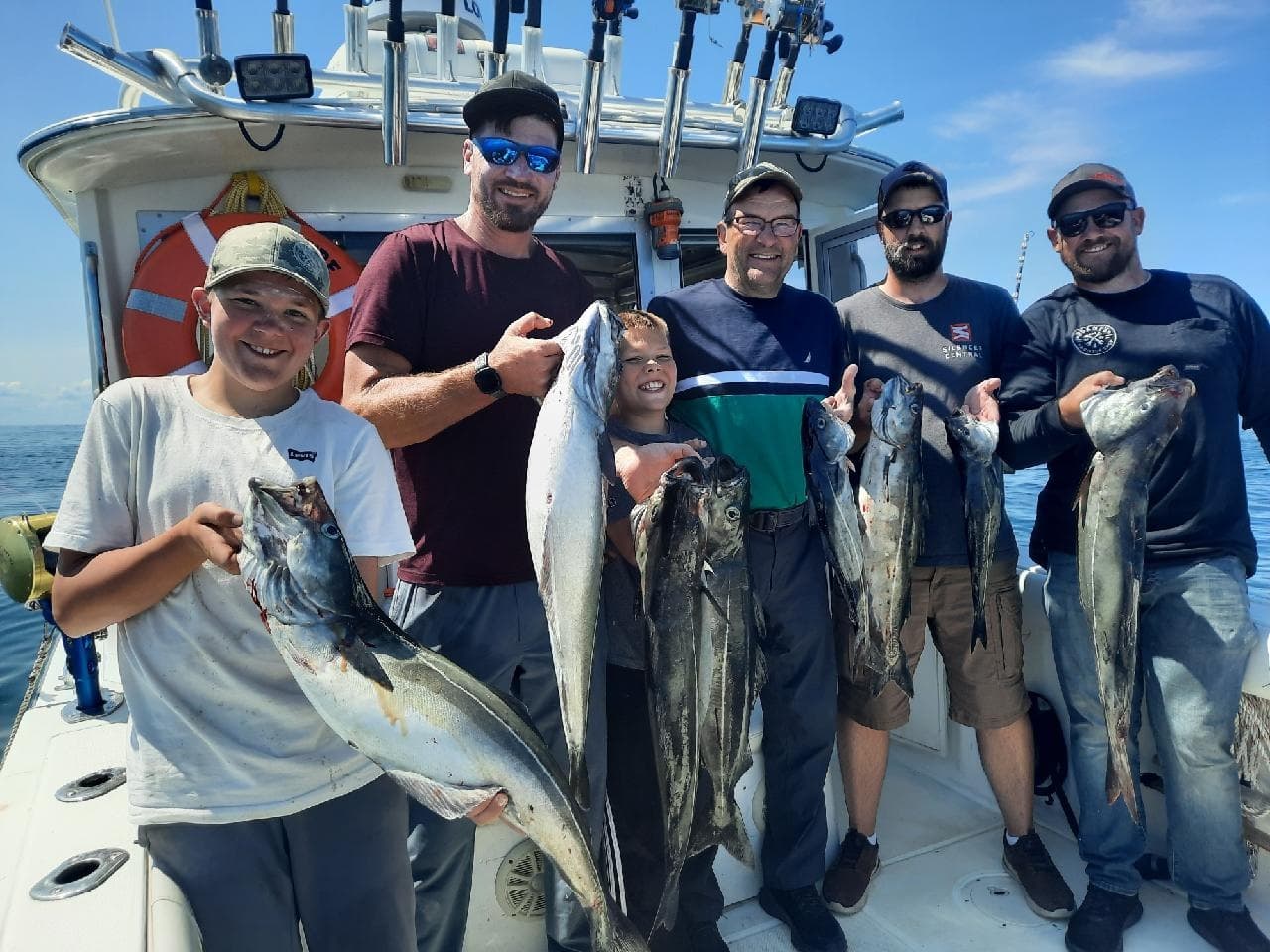 Group of anglers holding large catch aboard charter boat at sea