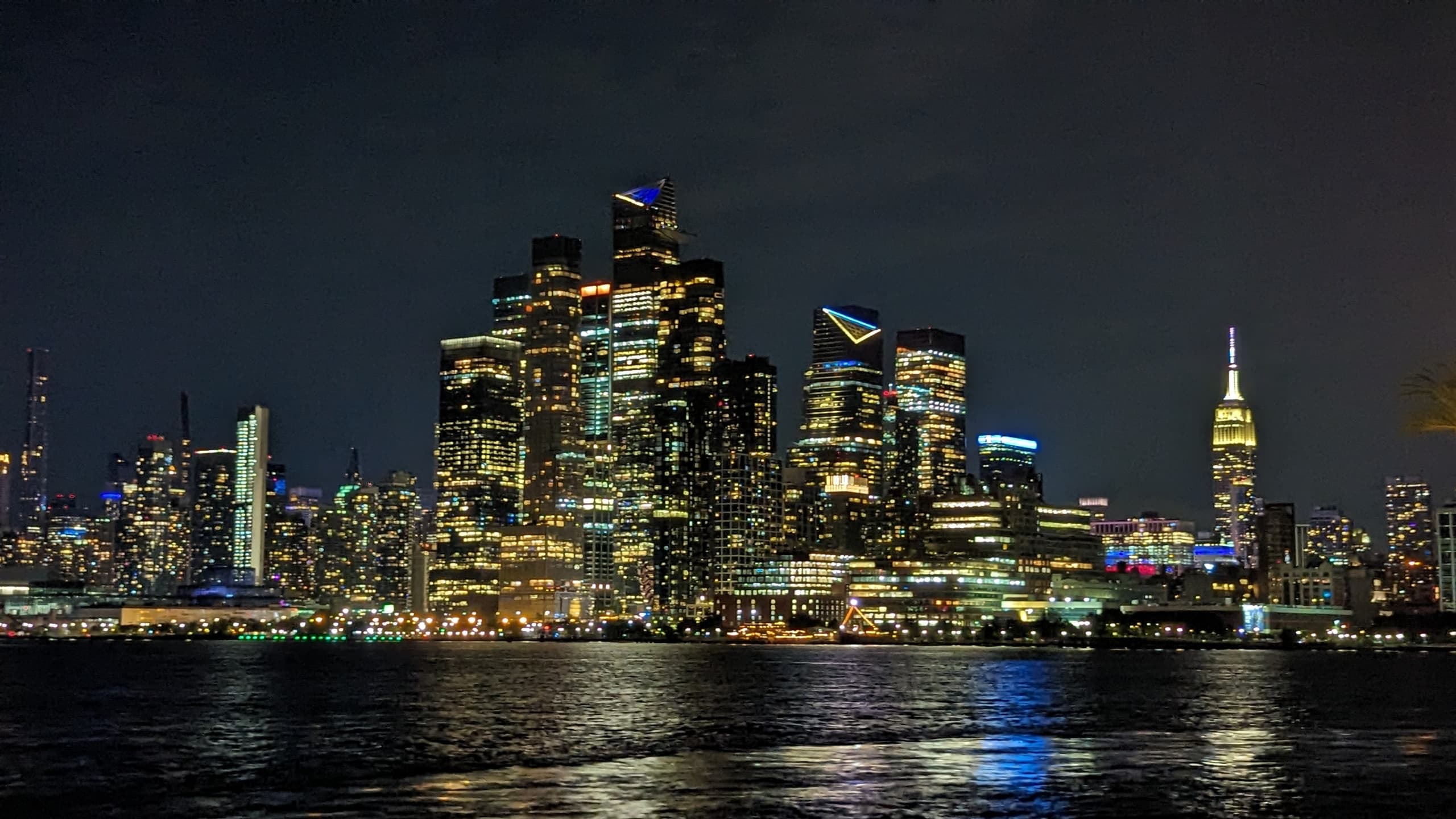 Nighttime New York skyline across harbor water, city lights