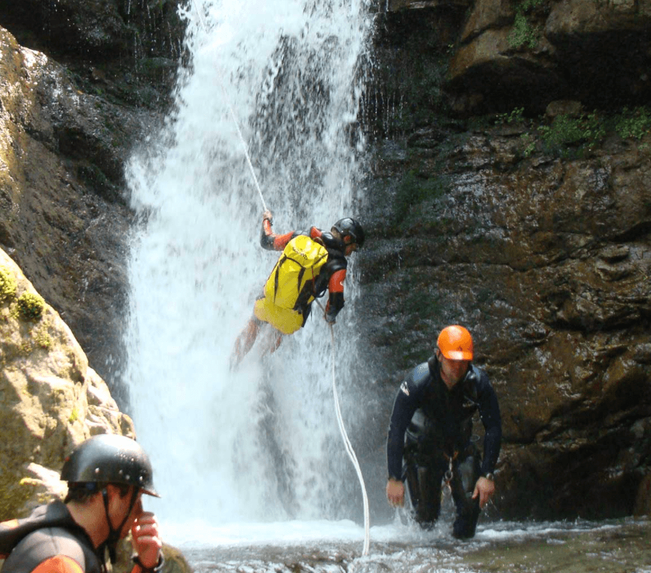 Canyoning team descending waterfall in rugged mountain canyon