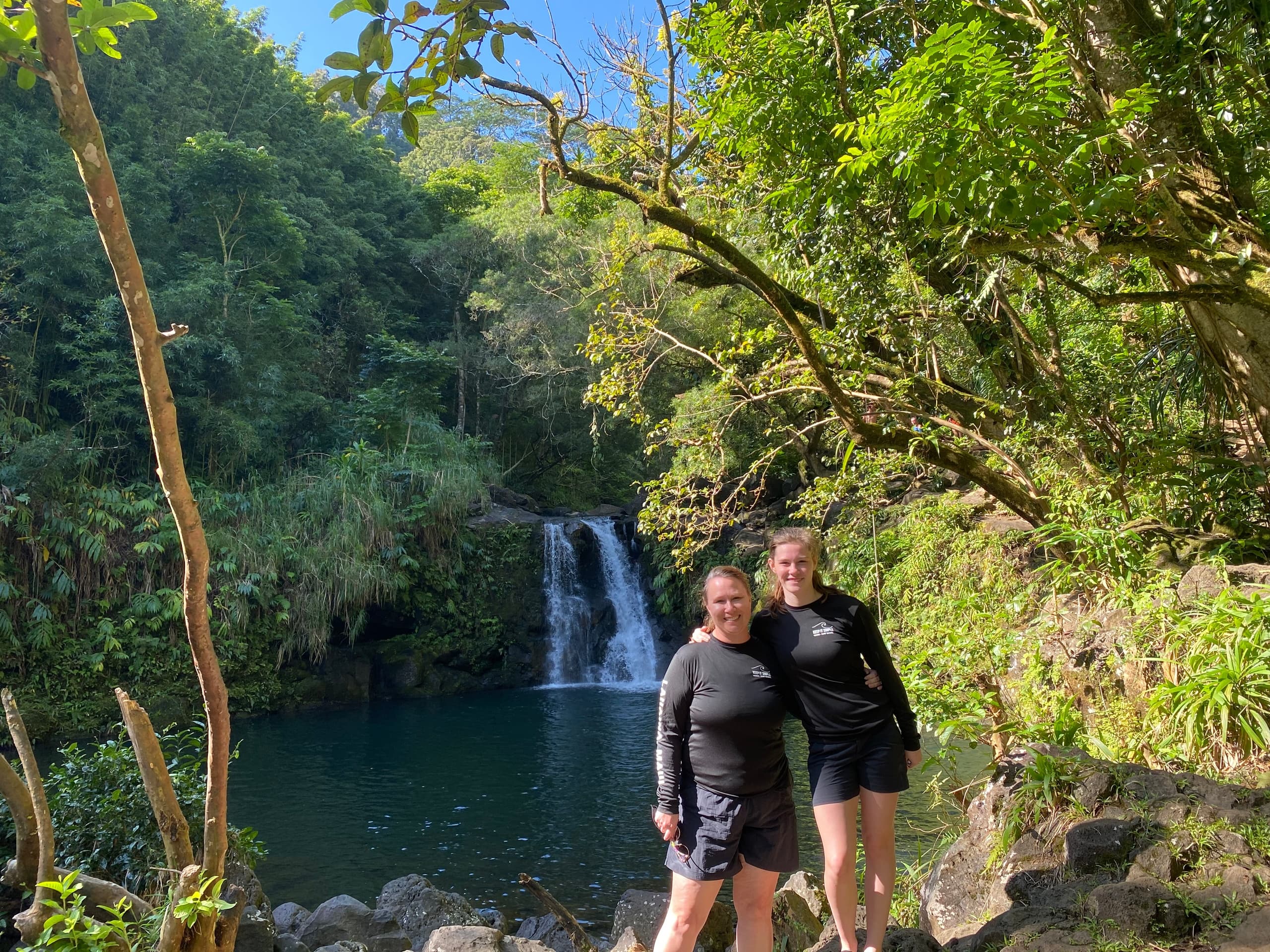 Couple standing by tropical waterfall pool in Hawaiian rainforest
