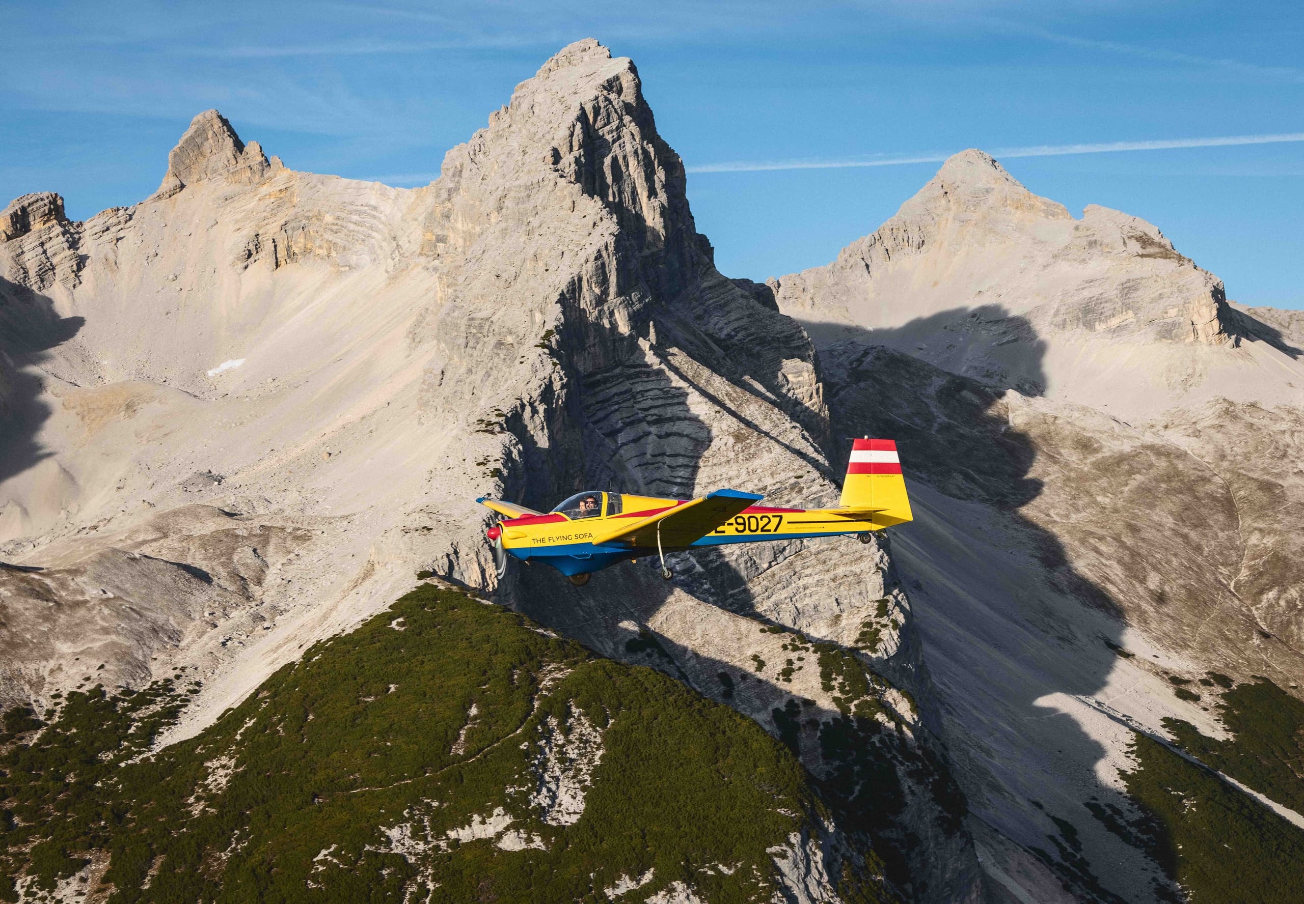 Light aircraft flying close to rugged limestone mountain peaks