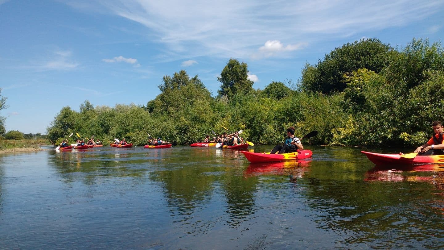 Group of kayakers paddling down scenic river through trees