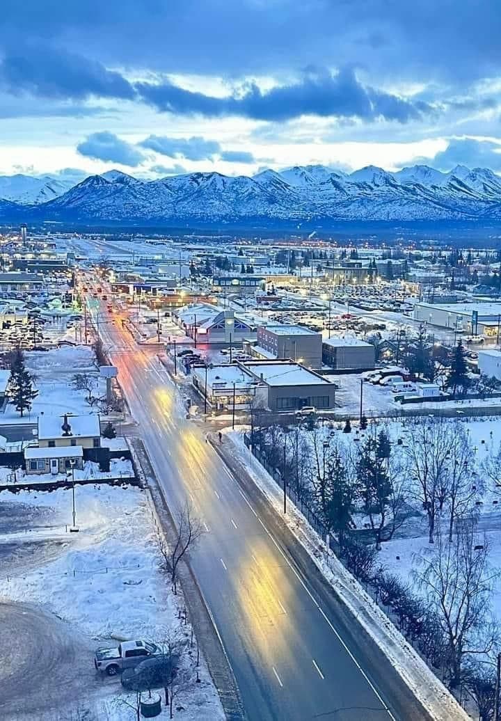 Aerial snowy town and mountain road leading to peaks
