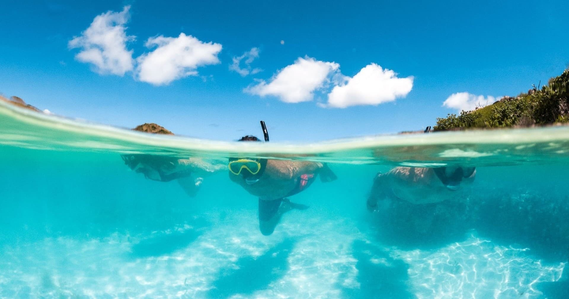 Snorkeler half-submerged in crystal-clear Caribbean lagoon waters