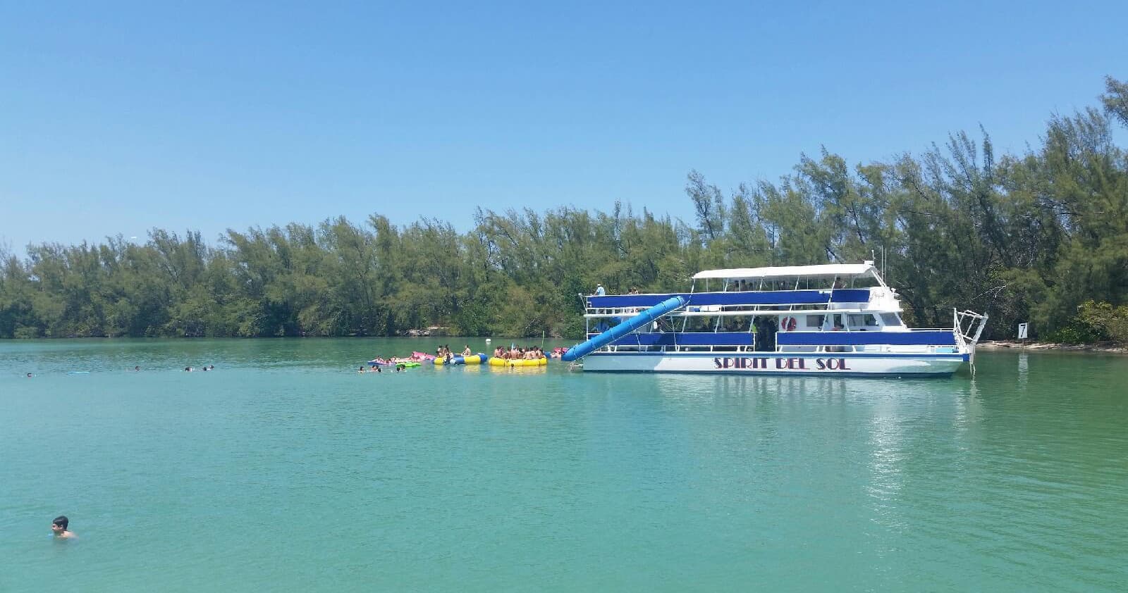 Cruise ship anchored in turquoise tropical bay with mangroves
