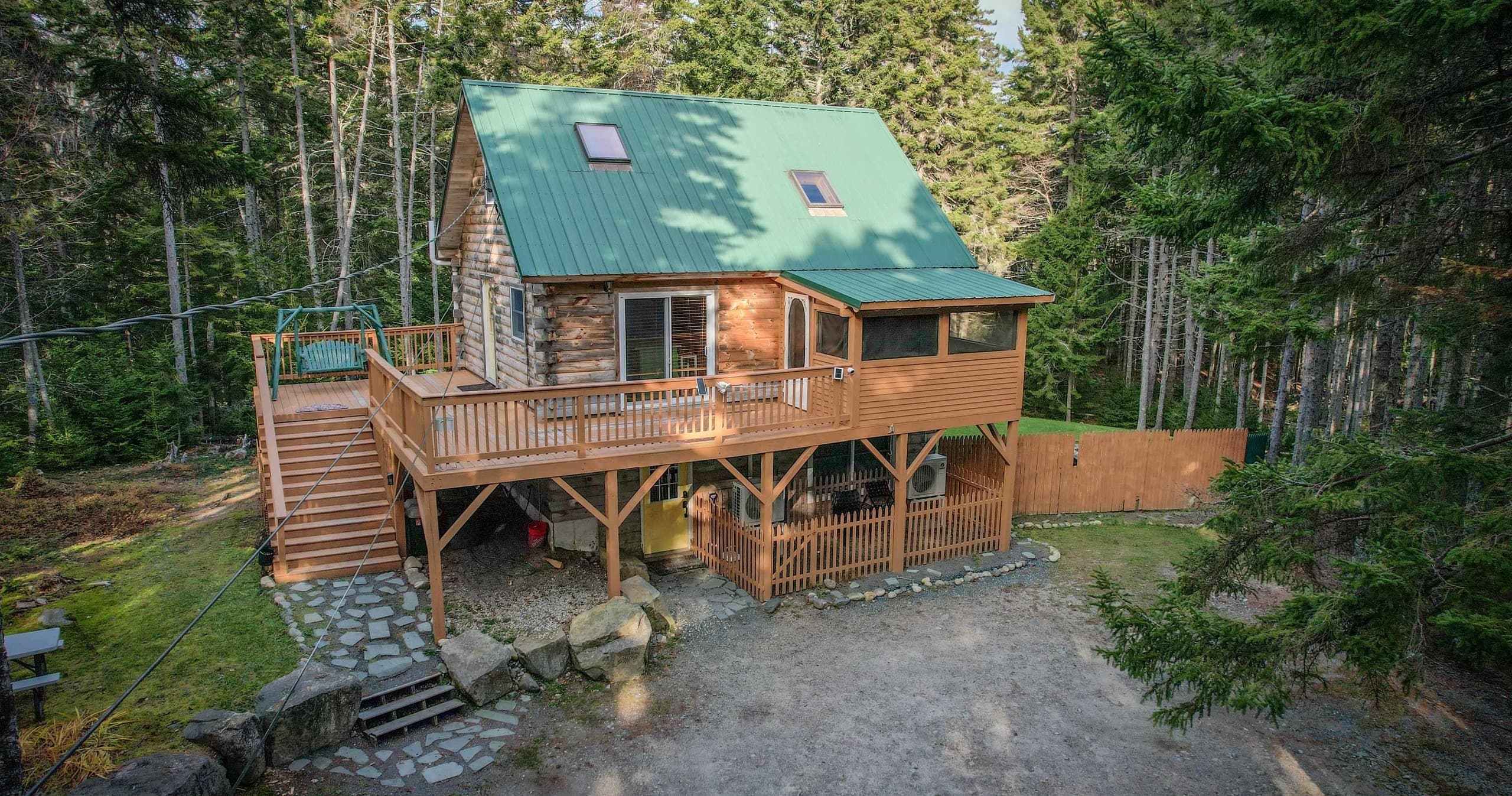 Rustic woodland cabin with wraparound deck among pine trees