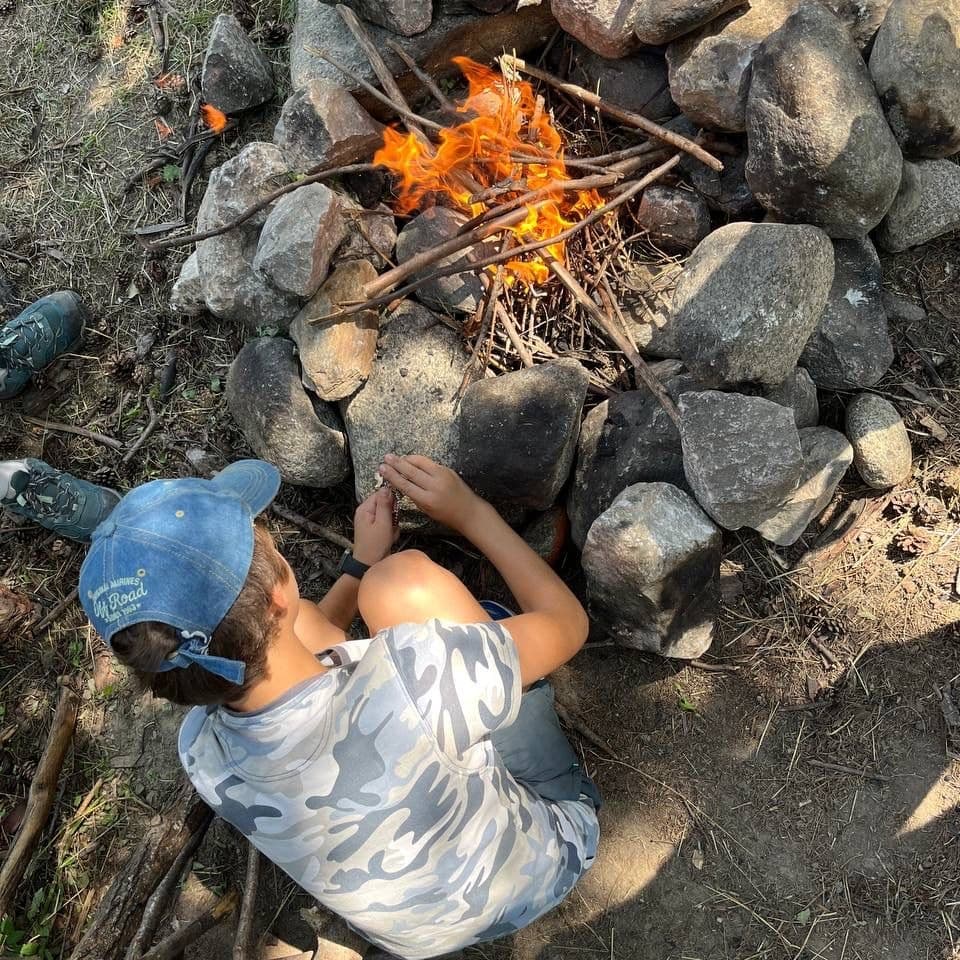 Child building campfire among rocks at alpine campsite in Marilleva