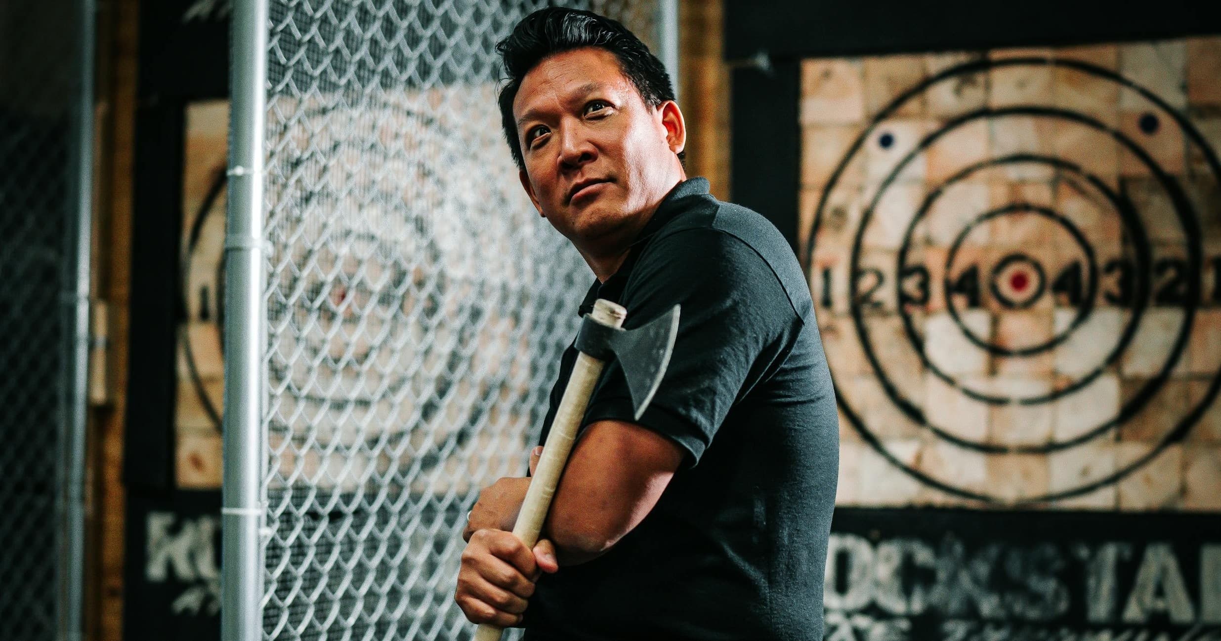 Man holding axe at indoor axe-throwing range, posing