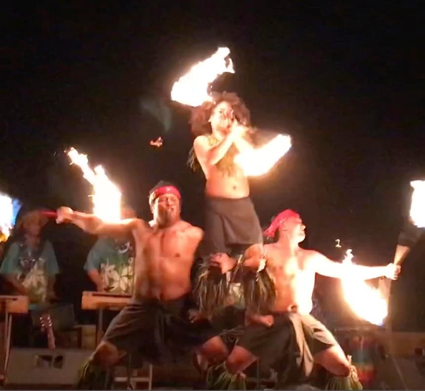Nighttime fire-dancing luau performers with torches on stage