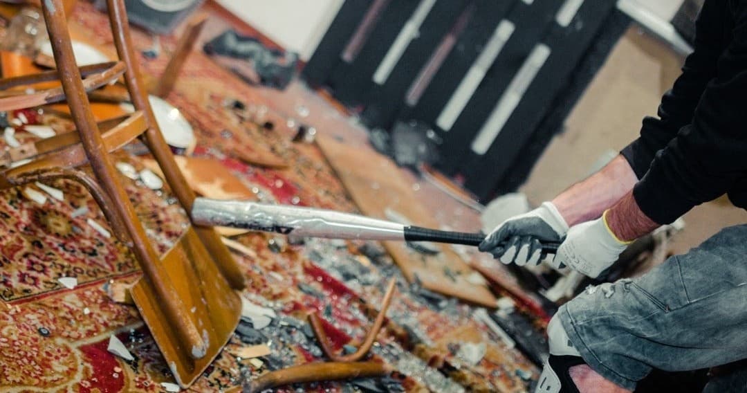 Person prying apart furniture with crowbar in indoor wrecking room