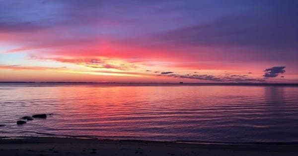 Vibrant coastal sunset over calm ocean, ideal for beach walks